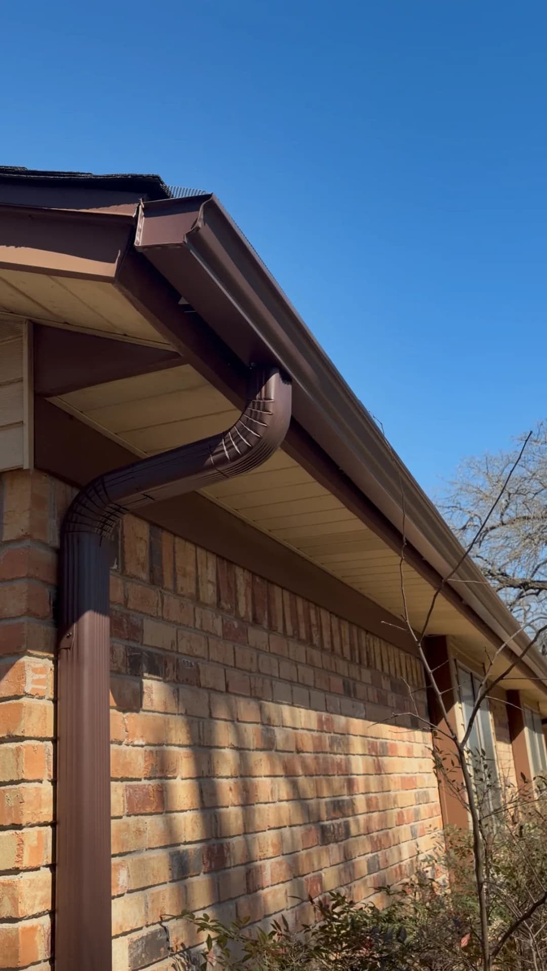 Brown gutter system on a house with clear blue sky in the background.